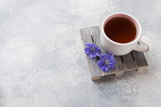 Photo cup with chicory drink and blue chicory flowers on grey table