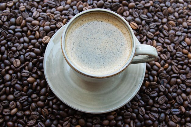 Cup with coffe on the roasted coffe beans