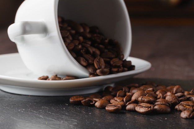 Cup with coffee beans on dark surface