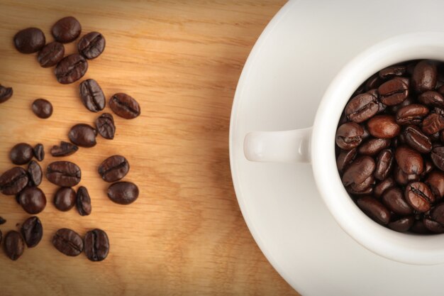 A cup with coffee and coffee beans on wood background