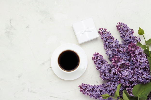 Cup with a coffee, a gift box and beautiful branches white surface