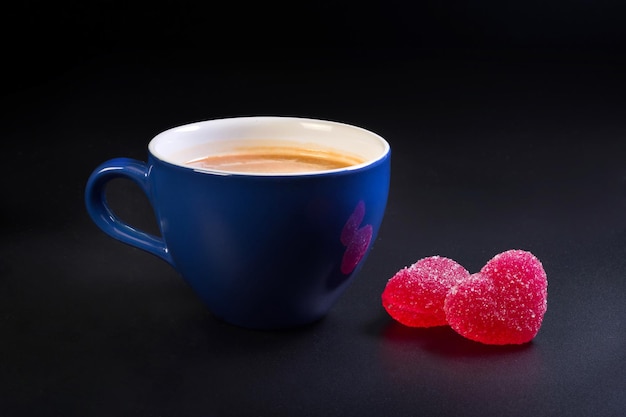 A cup with coffee and marmalade candies at the white background