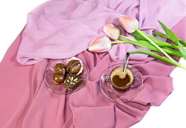 Cup with coffee pastries and pink tulips on a table closeup