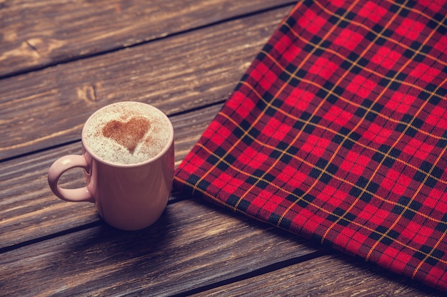 Cup with coffee and shape of the cacao heart on it and scarf.