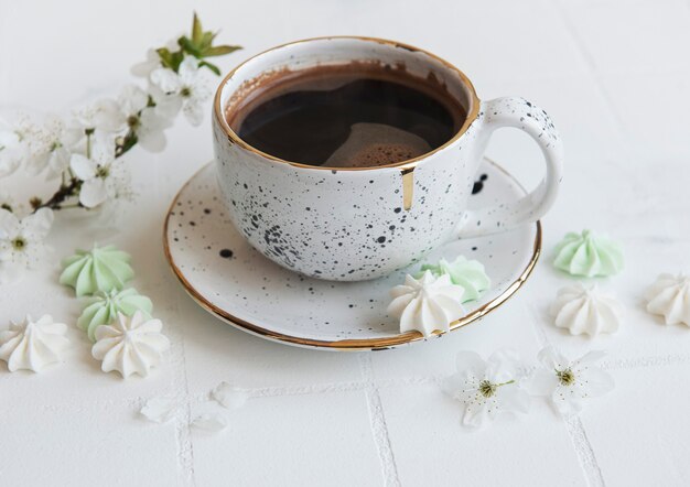 Cup with coffee and small meringues on a tiled background