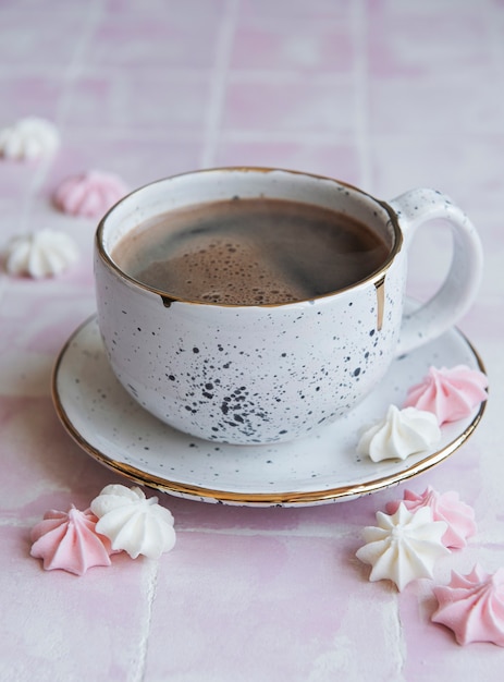 Cup with coffee and small meringues on a tiled surface