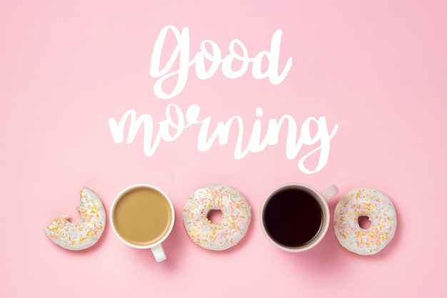 Чашка с кофе или чаем, свежие вкусные сладкие пончики на розовом фоне. Добавлен текст Доброе утро. Концепция пекарня, свежая выпечка, вкусный завтрак, фаст-фуд.