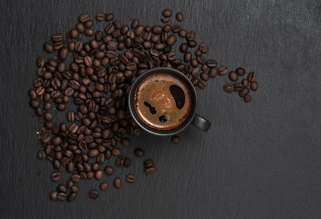 Cup with espresso, around a cup of coffee beans