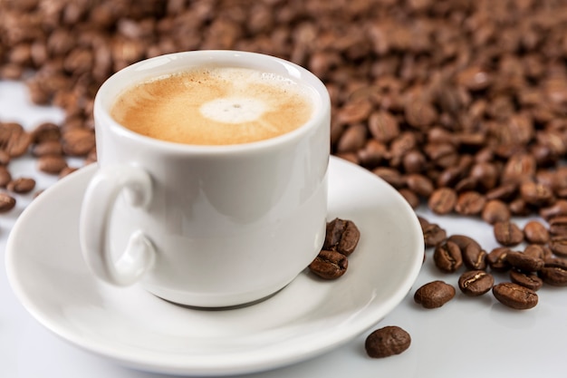 Cup with freshly brewed coffee and grains scattered