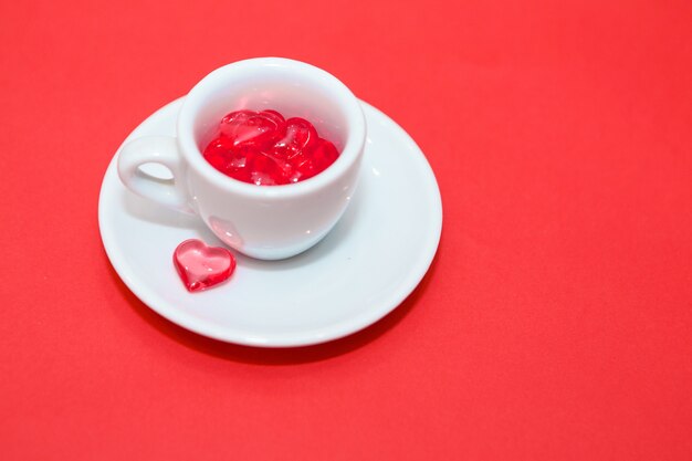 Cup with hearts on a red background. the view from the top. red hearts spilled out. isolated on a pink background. copy space