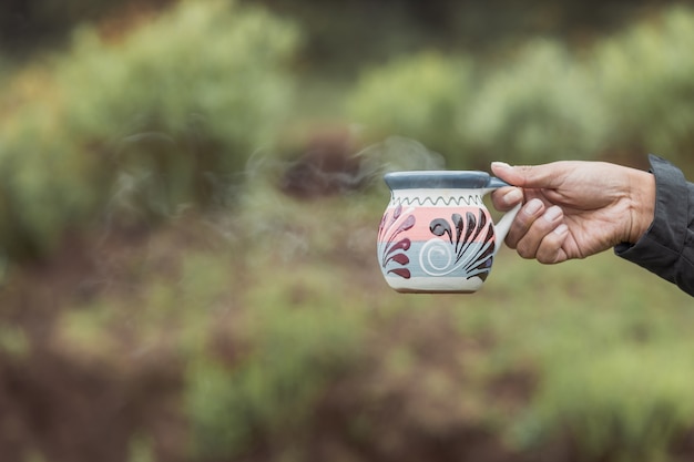 Cup with hot beverage in the forest