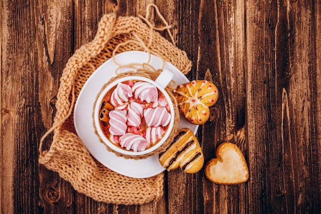 Tazza con cioccolatini caldi e marshmallow si trova sul tavolo con i biscotti