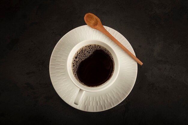 Cup with hot coffee on the dark table