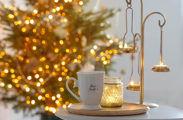 Cup with hot drink on background christmas tree