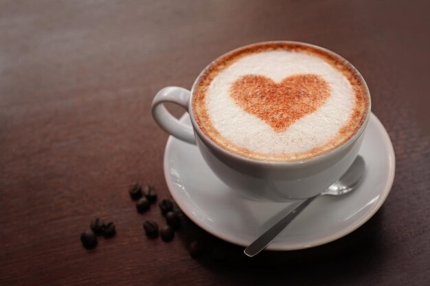 Cup with hot tasty coffee on wooden table close up view