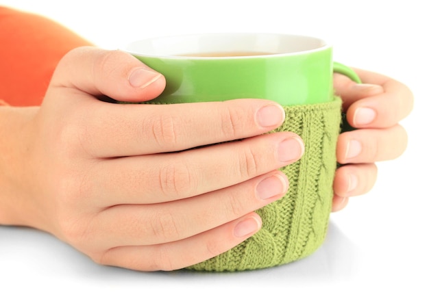 Cup with knitted thing on it in female hands isolated on white