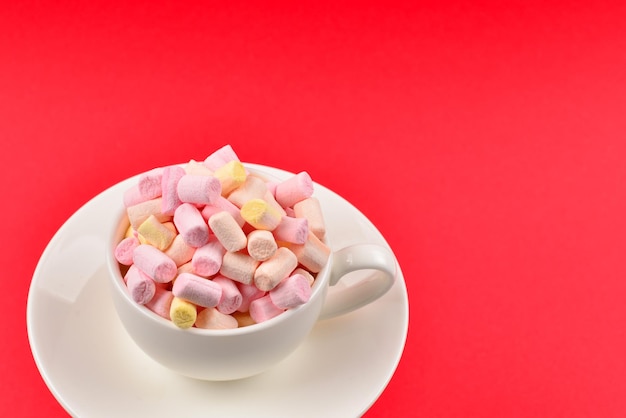 Cup with marshmallow on a red background. Copy space.