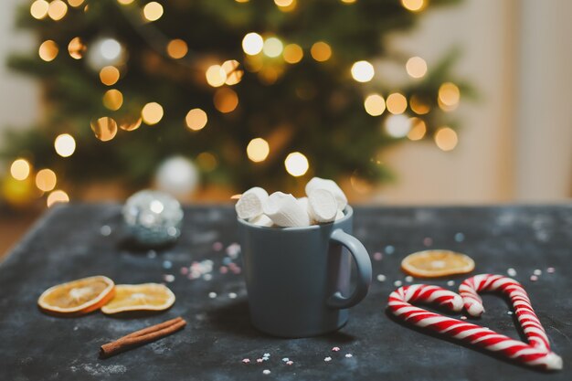 Tazza con marshmallows canna da zucchero mandarini sullo sfondo dell'albero di natale anno nuovo ancora vita