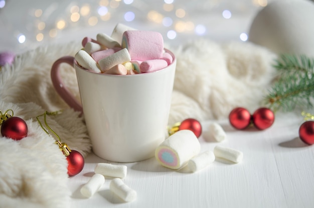 Cup with marshmallows and red balls on a white table