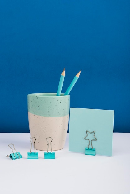 Cup with pencils and paperclips placed on desk with clipped memo with important message crutial