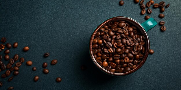 Foto una tazza con chicchi di caffè robusta o arabica arrostiti vista superiore su uno sfondo scuro