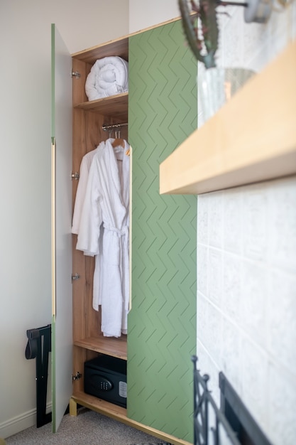 Photo cupboard. open green wardrobe with white bathrobe and rolled blanket in the living room