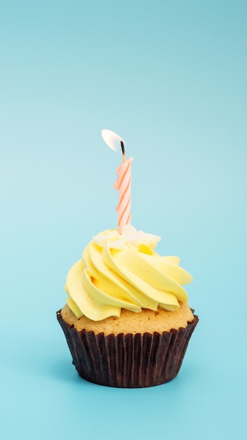 Cupcake and candle on a blue background.