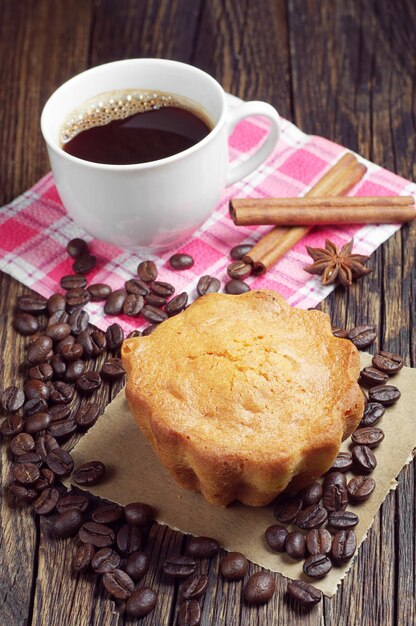 Cupcake, coffee cup and beans on old wooden table