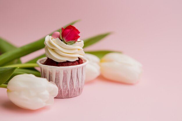 cupcake en witte tulpen op een roze achtergrond, ruimte voor tekst