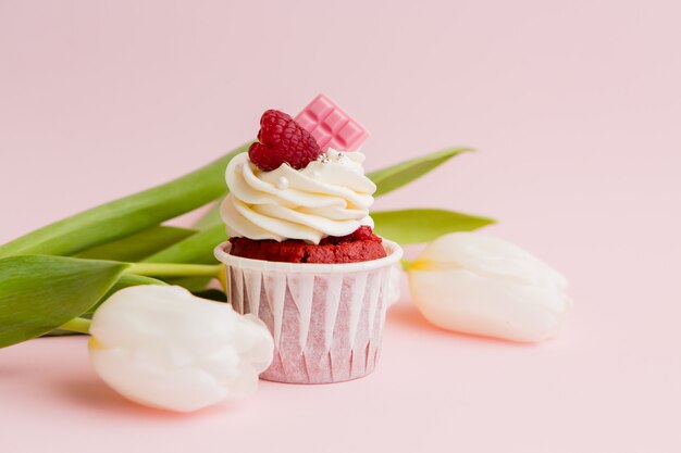 cupcake en witte tulpen op een roze oppervlak, ruimte voor tekst