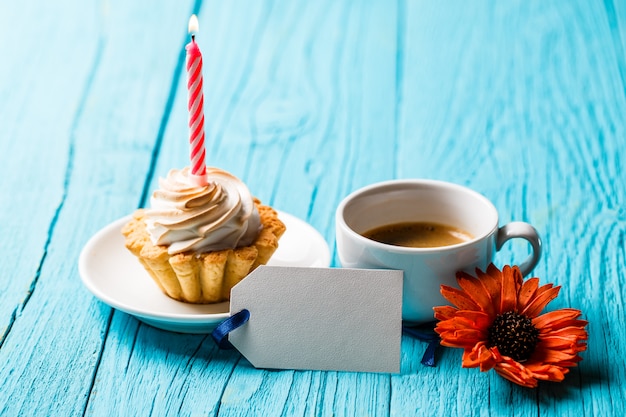 Cupcake met kaars in de buurt van koffie en bloem