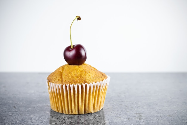 Cupcake met verse kersen close-up op grijze granieten tafel