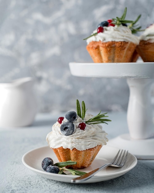 Cupcake (muffin) met bosbes en rozemarijnbotercrème op een grijze foto. high key, zelfgemaakte gebakken goederen