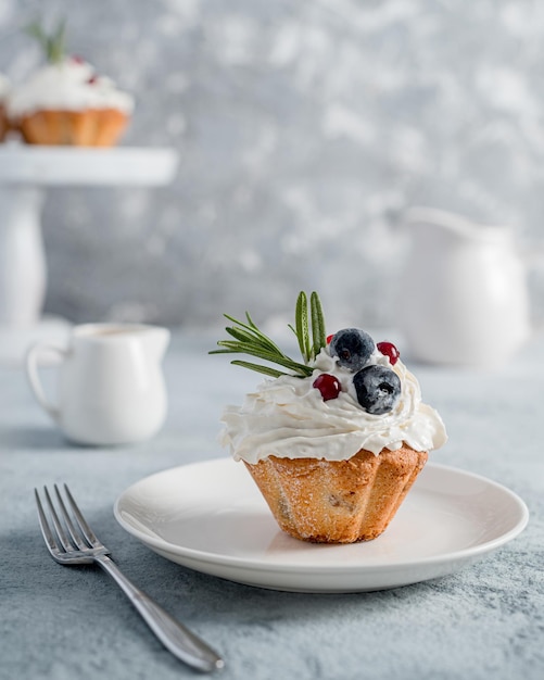 Cupcake (muffin) with blueberry and rosemary butter cream on a gray photo. High key, homemade baked goods