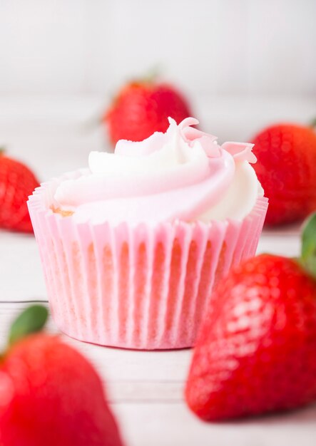 Cupcake muffin with strawberry cream dessert on wooden table with fresh strawberries