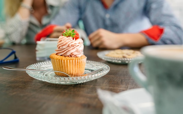 Cupcake in a pastry shop with couple holding hands in background