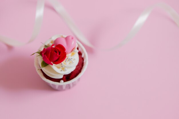 cupcake roses and hearts on a pink ..Chocolate cupcakes decorated with cream rose