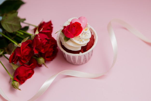 cupcake roses and hearts on a pink ..Chocolate cupcakes decorated with cream rose