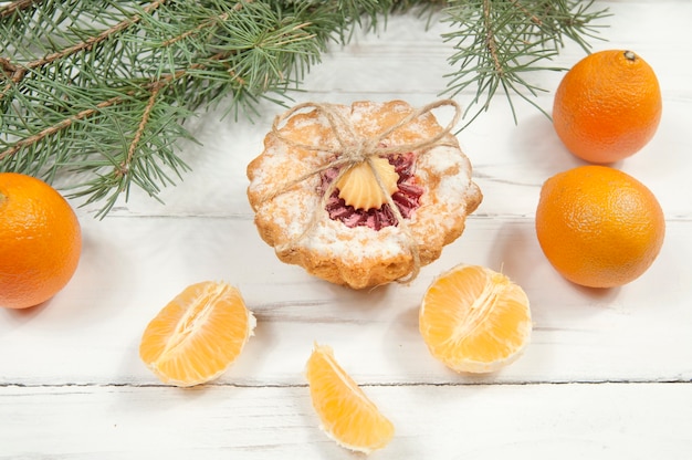 Cupcake tangerines and Christmas tree branches on a white wooden table