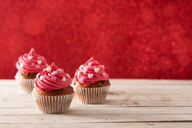 Cupcake versierd met suikerharten en een cupido-pijl voor valentijnsdag op houten tafel