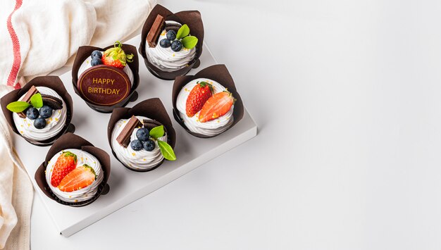 Cupcake on white table decorated with strawberry blueberry and happy birthday tag chocolate