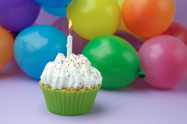 Cupcake with colorful birthday candle and balloons