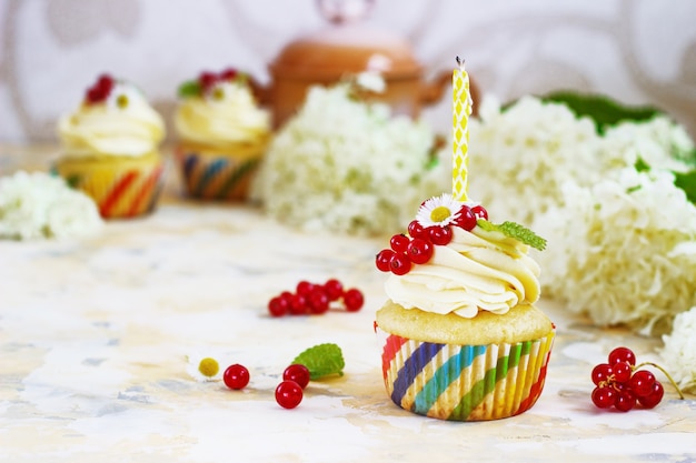 cupcake with cream and berries and a candle