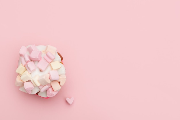 Foto cupcake con cuori di marshmallow su uno sfondo rosa con cuoricino vicino al muffin