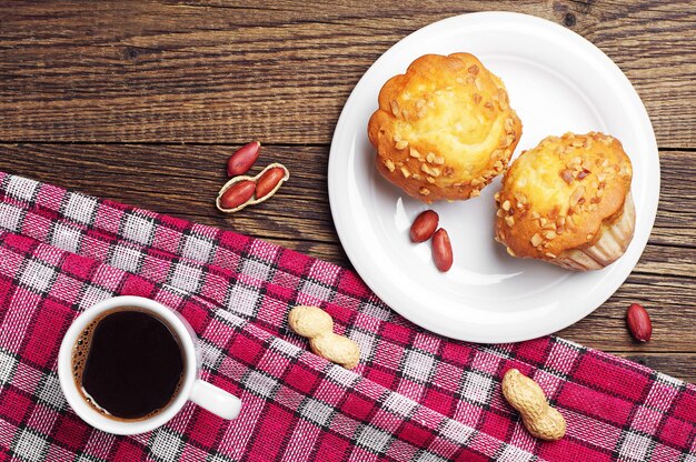 Cupcake with nuts and cup of coffee on wooden table Top view