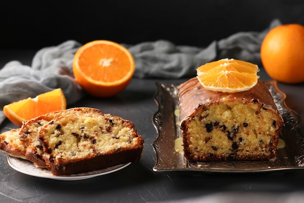 Cupcake with oranges and chocolate located on a tray against a dark background