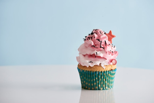 Photo cupcake with pink cream icing on table