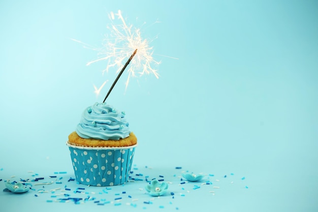 Photo cupcake with sparkler on blue background
