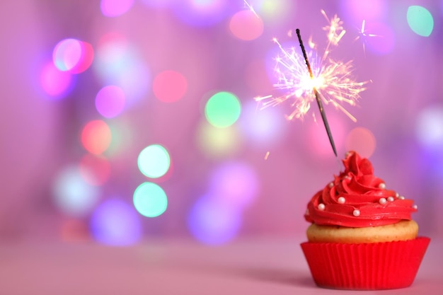 Cupcake with sparkler on defocused lights background