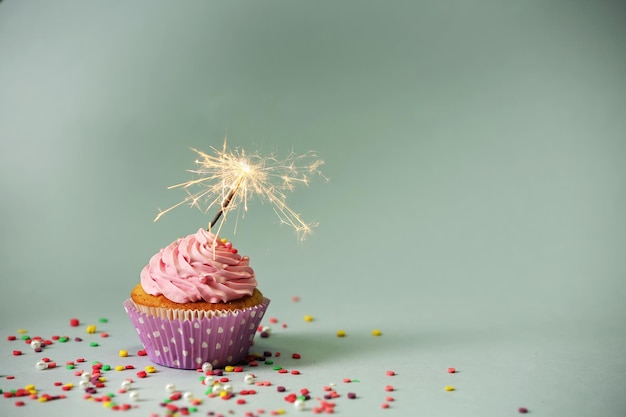 Cupcake with sparkler on grey background